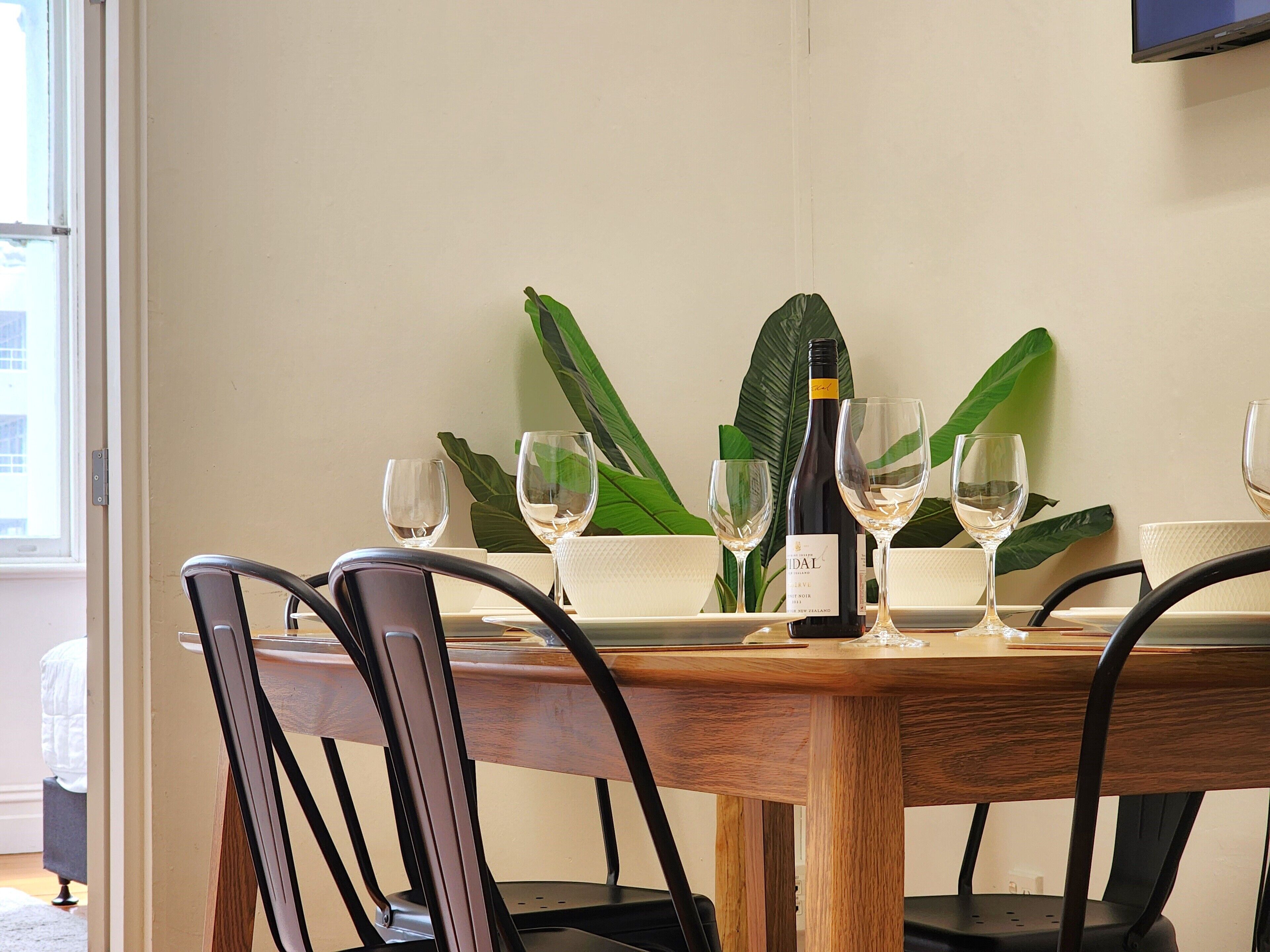 A dining table with four chairs, a bottle of wine, and two empty wine glasses.