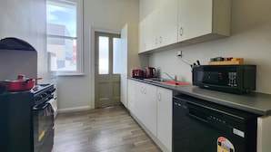 A compact kitchen with a stove, microwave, and dishwasher. - U Suites on Cuba (Wellington)