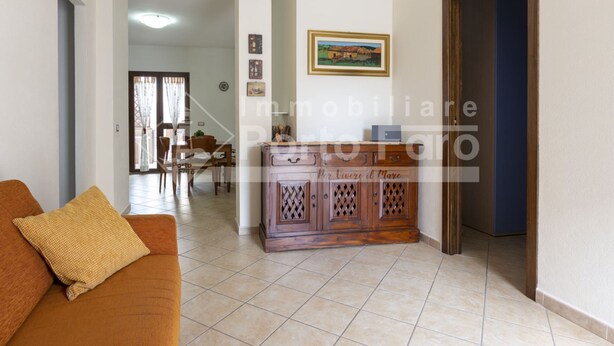 Uma sala de estar com sofá, um armário de madeira e um espaço de jantar com mesa e cadeiras.