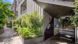 Un edificio moderno con un sendero estrecho bordeado por macetas con plantas verdes.