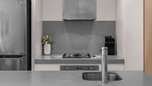 Una cocina moderna con refrigerador de acero inoxidable, estufa a gas, horno empotrado y pileta de acero inoxidable.
