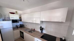 A modern kitchen with white cabinets, a microwave, a sink, and a coffee maker.