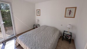 A bedroom with a bed, two bedside tables, a door, and a window.