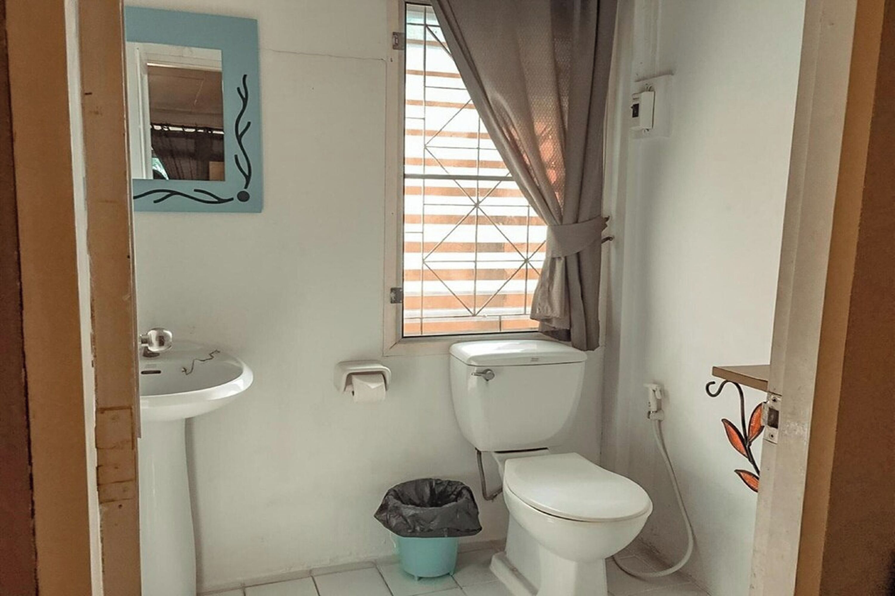 A small, compact bathroom with a toilet, sink, and window.
