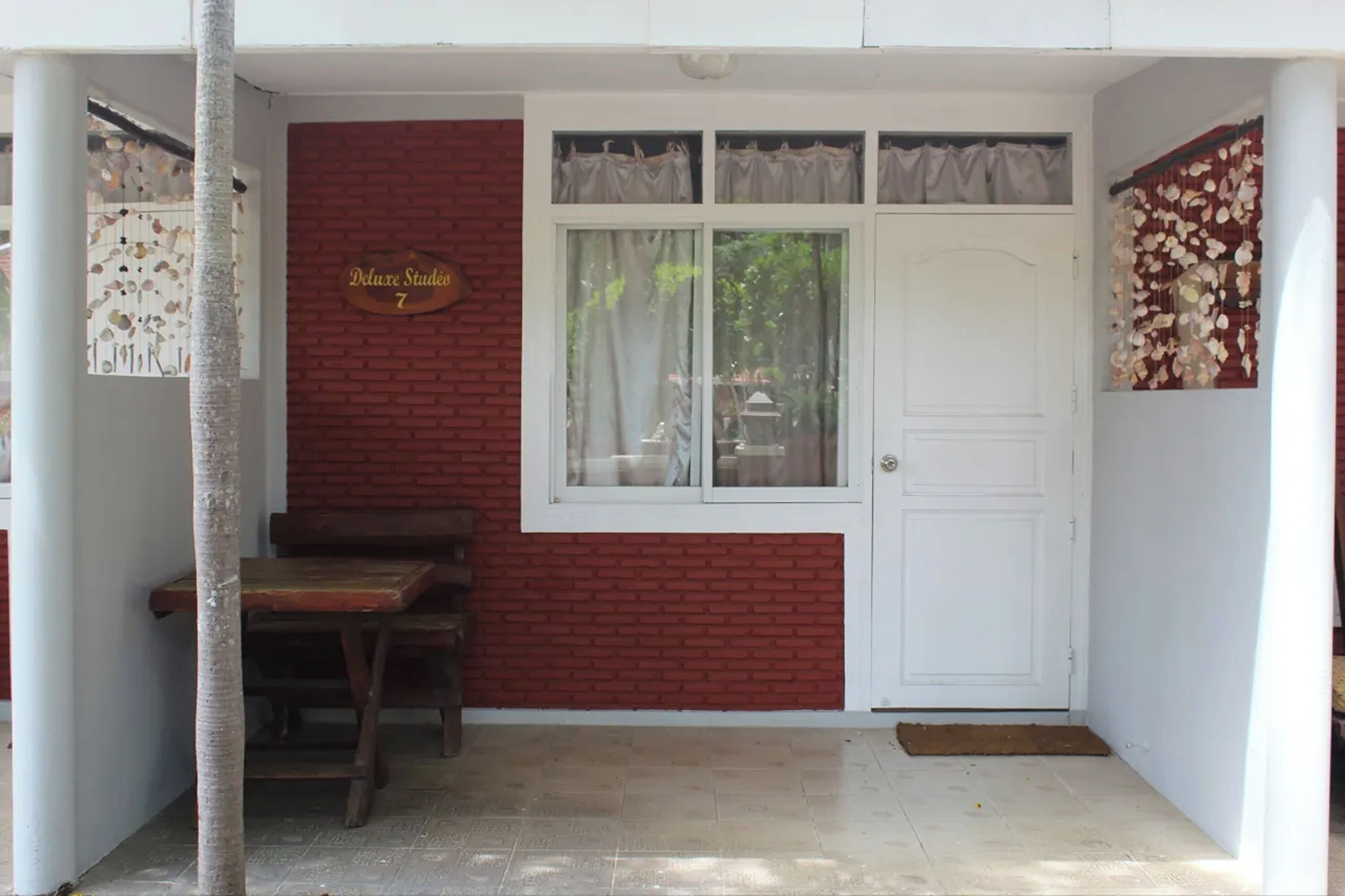 A room with a red brick wall, a white door, and a window with curtains.