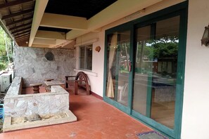 A covered outdoor area with a stone wall, a wooden bench, and a table. - Safari Riviera Resort (Pattaya)