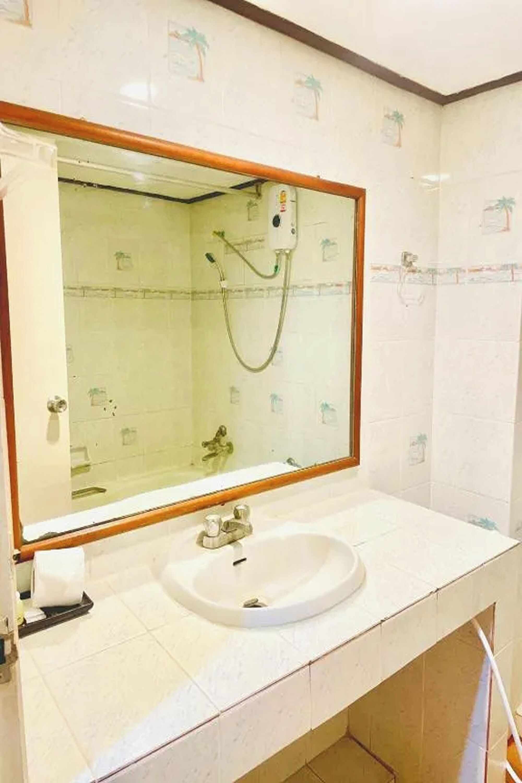 A bathroom with a large mirror, a sink, and a shower.