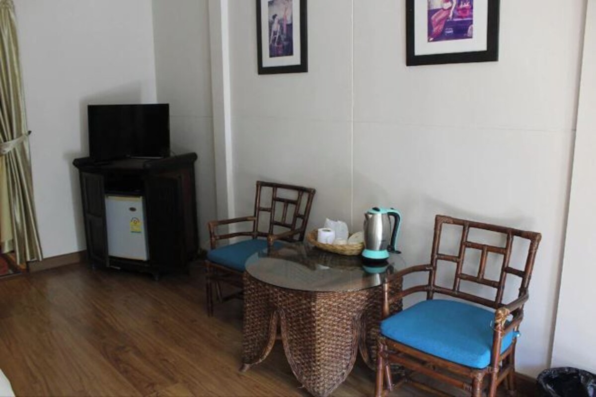 A small dining area with a round table, two chairs, a television, and a refrigerator.