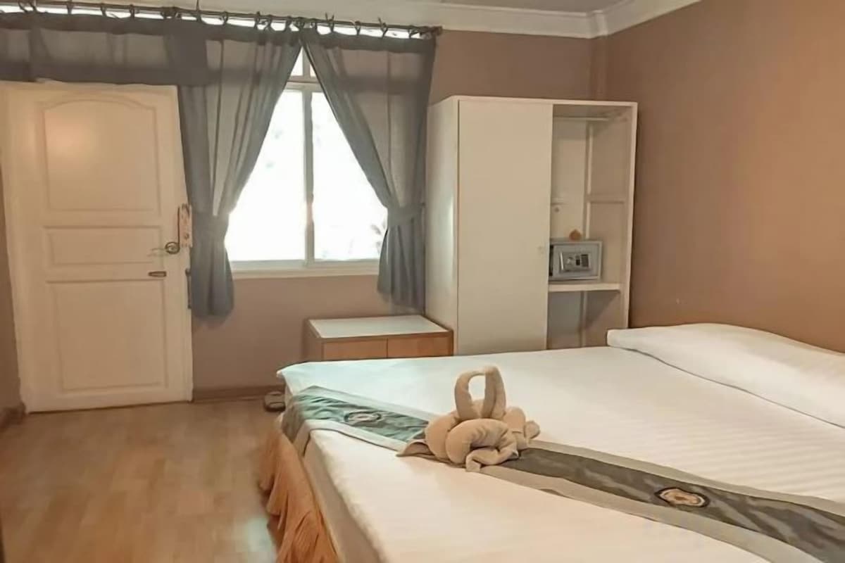 Una camera da letto con un letto, un armadio, una finestra con tende e un comodino.