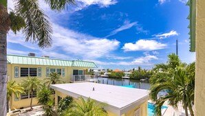 A view of a building with a green roof and a pool area with palm trees.
