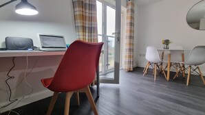 A modern room with a desk, laptop, and a red chair. There is a dining table with chairs and a mirror on the wall. - Spacious London Apartment, 5mins from metro (London)