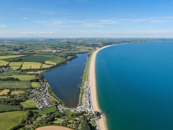 An aerial view of a coastal town with a long beach, green fields, and a river. - Swan's Nest - River view, Close to beach, Garden (Torcross)