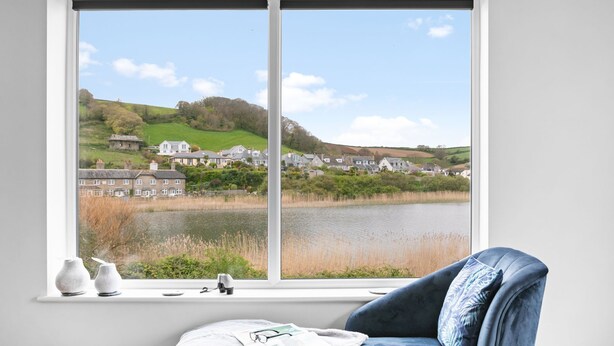 A room with a large window overlooking a lake and houses. - Swan's Nest - River view, Close to beach, Garden (Torcross)