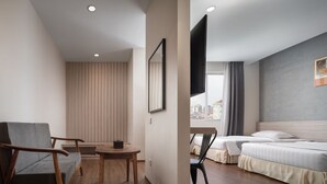 A hotel room with a bed, a chair, a table, and a TV mounted on the wall. - Joli Hotel (Phnom Penh)