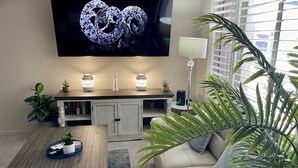 Een moderne woonkamer met een flatscreen televisie, een houten salontafel, een bank en een boekenkast.