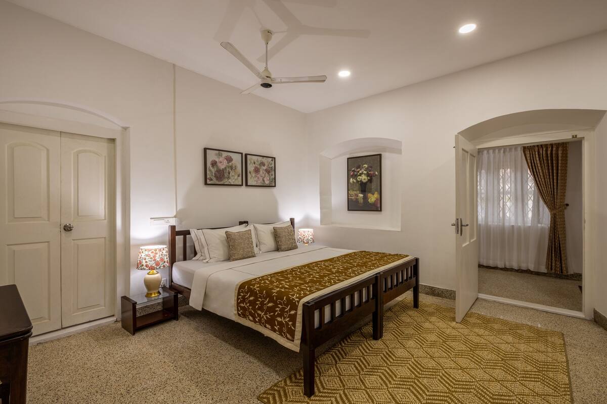A bedroom with a bed, bedside table, lamp, and a ceiling fan.