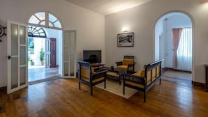 Amplia sala de estar con piso de madera, ventilador de techo y televisor. Hay dos sofás y una mesa de centro.