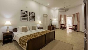 Una habitación de hotel con cama, mesitas de noche, ventilador de techo y cuadros en la pared.