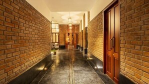 A corridor with brick walls and a polished floor, leading to a door with a wooden frame.