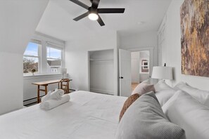 Une chambre moderne avec un grand lit, un bureau et un ventilateur de plafond.