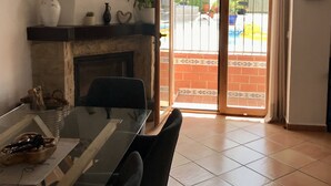 A dining area with a glass table, chairs, a fireplace, and a view of a pool through a glass door.