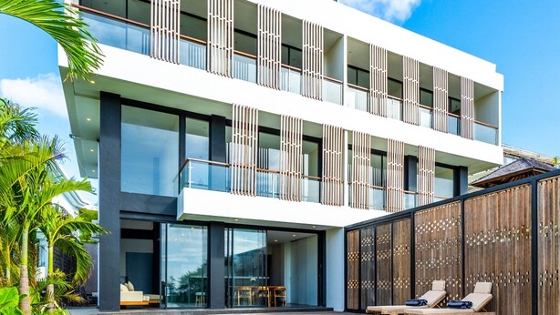 A modern hotel with a pool, large windows, and a wooden fence.
