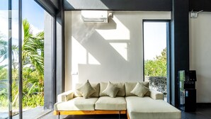 A modern living room with a sectional sofa, large windows, and a water dispenser.