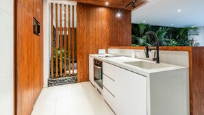 A modern kitchen with wooden accents, a built-in oven, and a white countertop. - Amazing 3BR Green Flow Villa in Ubud with Pool (Kec. Ubud)