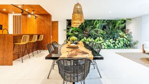 A modern dining area with a wooden table, black chairs, and a hanging light fixture. - Amazing 3BR Green Flow Villa in Ubud with Pool (Kec. Ubud)