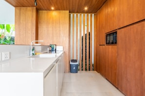 A modern kitchen with a white countertop, stainless steel sink, and a microwave. - Amazing 3BR Green Flow Villa in Ubud with Pool (Kec. Ubud)