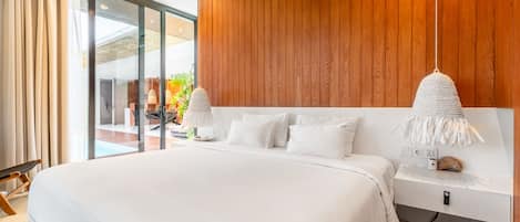 A modern bedroom with a large bed, wooden panel walls, and a view of a pool and outdoor seating area.