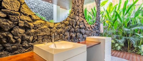 A bathroom with a stone wall, two sinks, and a mirror.