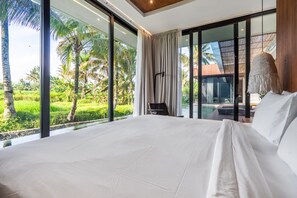 A bedroom with a large bed, a view of a pool, and a tropical landscape. - Amazing 3BR Green Flow Villa in Ubud with Pool (Kec. Ubud)
