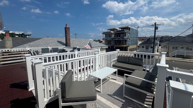 Terraza en la azotea con mobiliario exterior, una bandera y vistas de la ciudad.