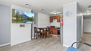Eine moderne Küche mit Holzausstattung, einem Edelstahlkühlschrank und einem Essbereich mit Tisch und Stühlen.