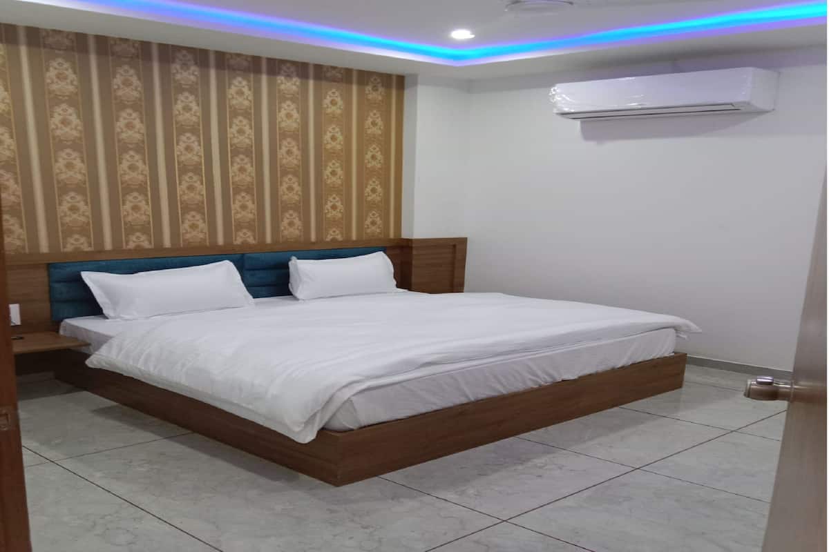 Una camera da letto con un letto di legno, biancheria da letto bianca, carta da parati decorata, una ventola a soffitto e un condizionatore d'aria.