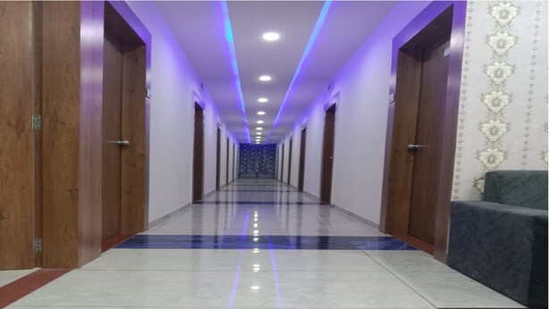 A hotel corridor with a checkered floor, wooden doors, and a patterned wall.