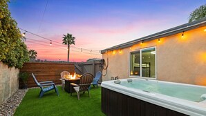 Patio con jacuzzi, fogata y mobiliario exterior.