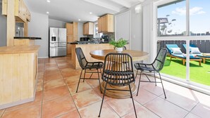 Una cocina moderna con armarios de madera, una isla central y un comedor con sillas.
