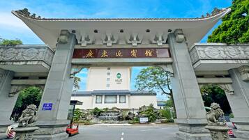 Una puerta tradicional china con un letrero, un edificio con un letrero y una estatua en primer plano.