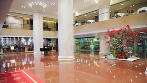 A spacious lobby with a red carpet, marble columns, and a large floral arrangement. - Guangdong Yingbin Hotel (Guangzhou)