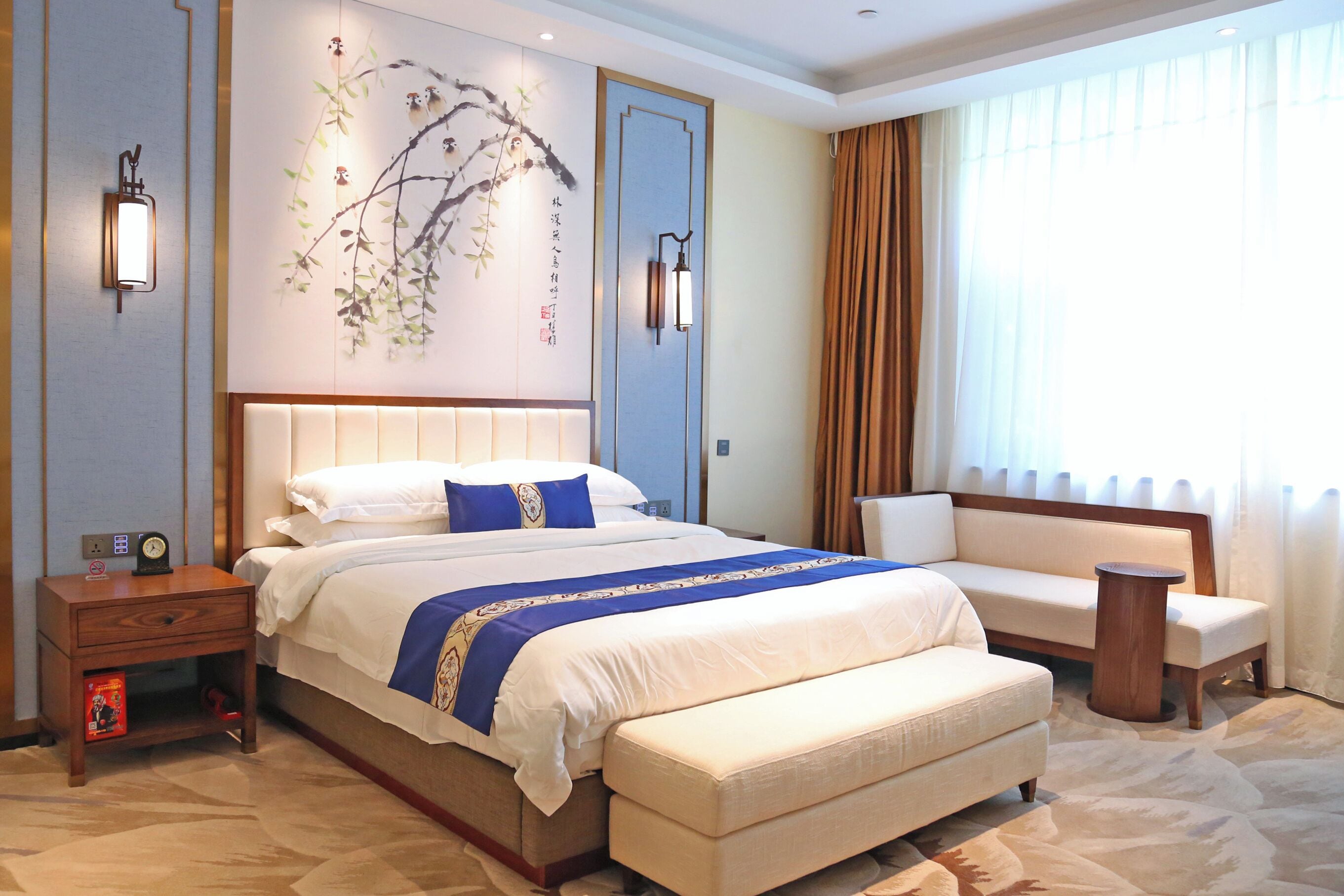 A hotel room with a large bed, a sitting area, and a decorative wall with artwork.