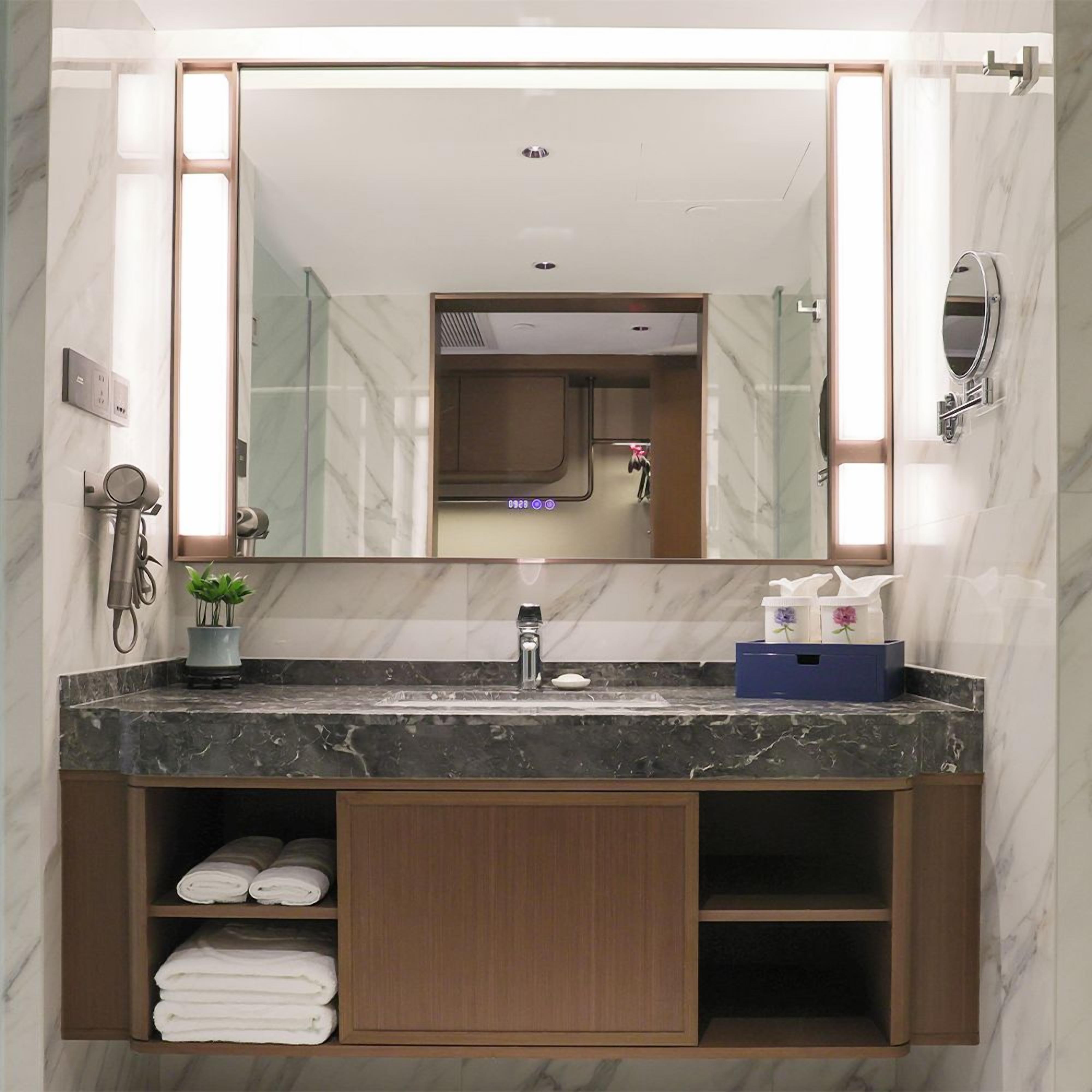 A modern bathroom with a marble vanity, a large mirror, and a built-in shower.