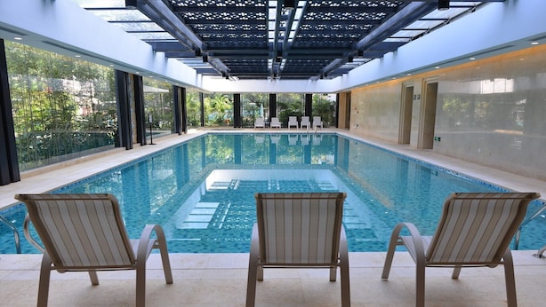 An indoor swimming pool with clear blue water, surrounded by lounge chairs and a glass ceiling. - Guangdong Yingbin Hotel (Guangzhou)