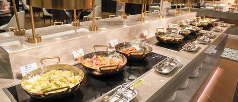 A buffet setup with multiple serving stations, each with a variety of dishes and utensils.