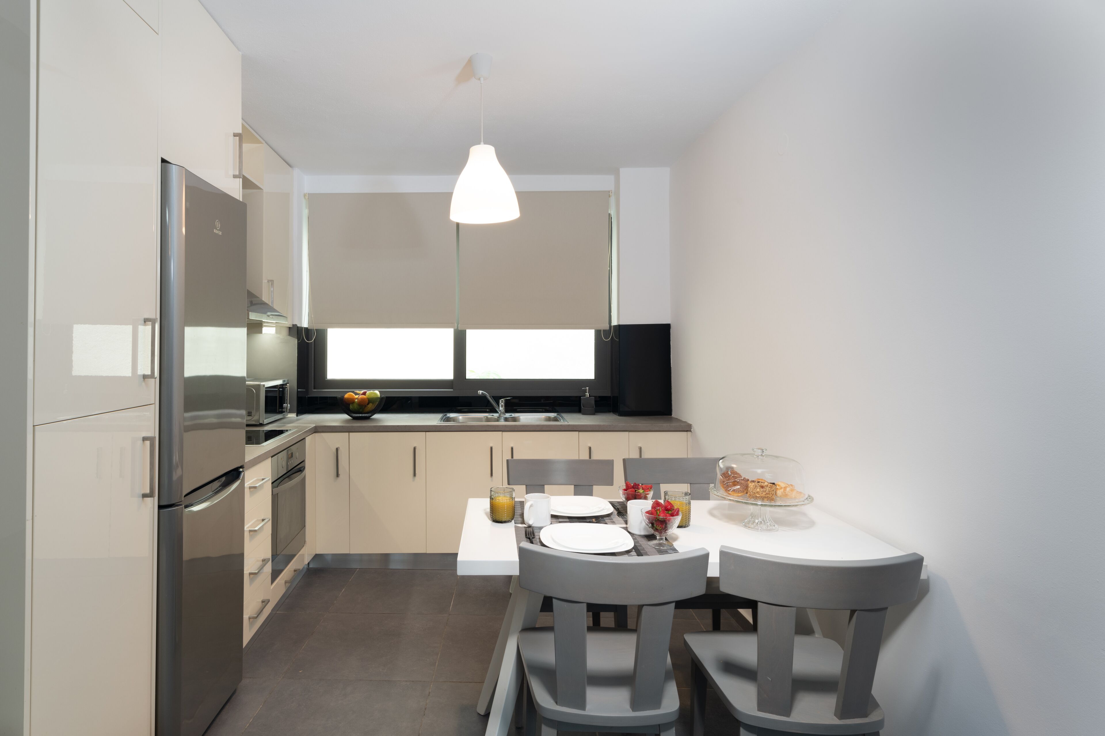 Una cucina moderna con zona pranzo, elettrodomestici in acciaio inossidabile e una lampada a sospensione.