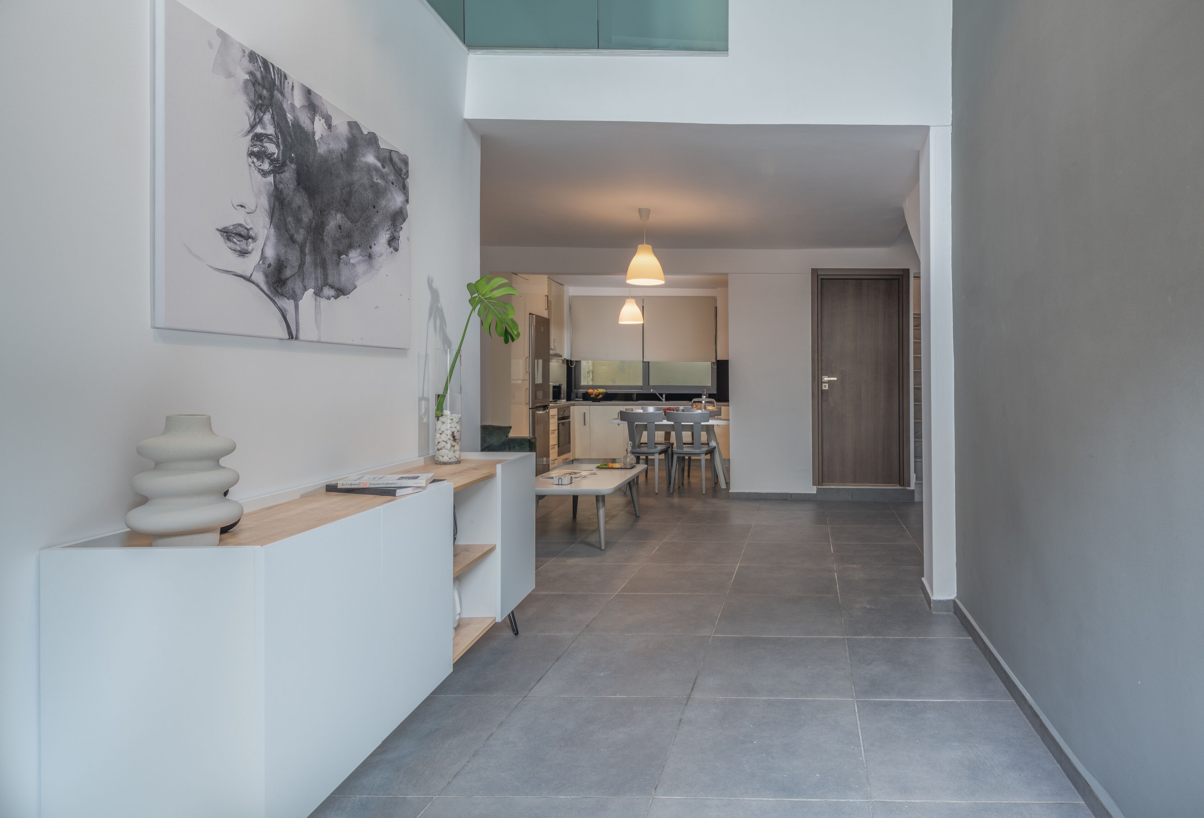 Et moderne interiør med et køkken, spiseområde og en gang der fører til en dør.