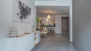 A modern interior with a kitchen, dining area, and a hallway leading to a door. - Zen Central Luxury Apartment (Heraklion)