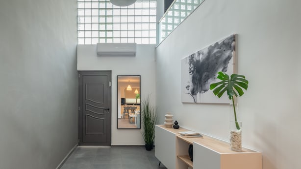 A modern hallway with a grey door, a potted plant, a console table, and a large abstract painting on the wall. - Zen Central Luxury Apartment (Heraklion)