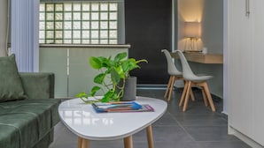 A modern living room with a white coffee table, a green sofa, and a potted plant. - Zen Central Luxury Apartment (Heraklion)